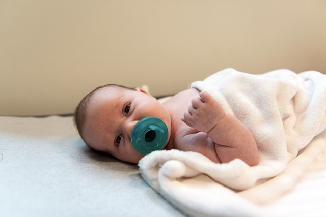 Baby swaddled in blanket lay on a flat surface